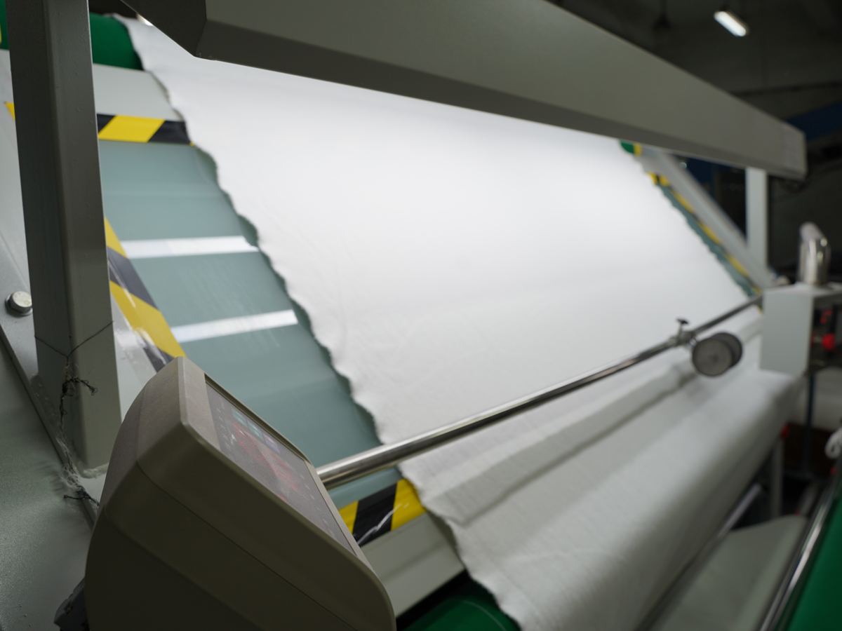 White fabric running through a fabric inspection machine